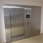 Esterilizador de vapor de doble puerta de Getinge integrado en una mampara de sala limpia, con pantalla táctil y manómetro de la cámara